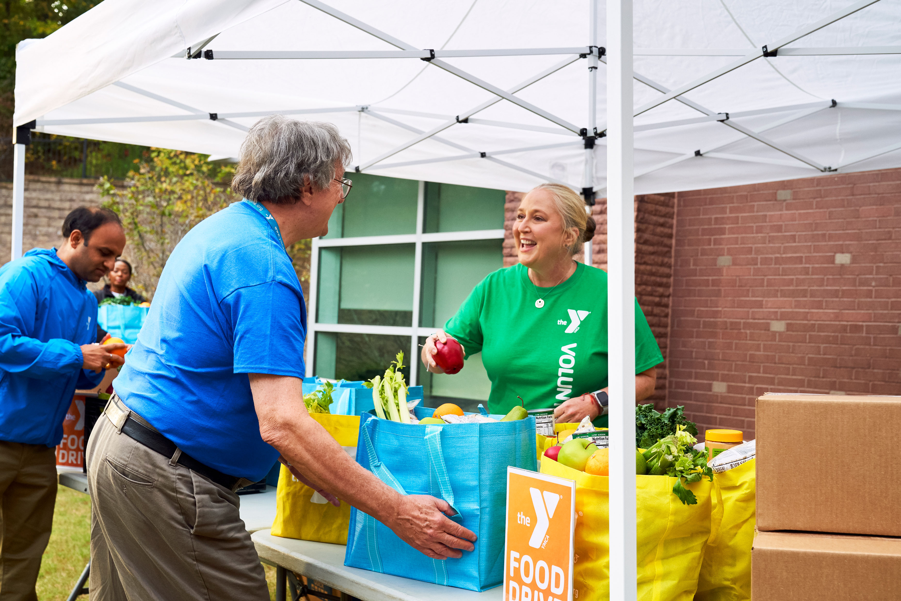 Y volunteers handling fresh produce at food drive Y volunteers handling fresh produce at food drive