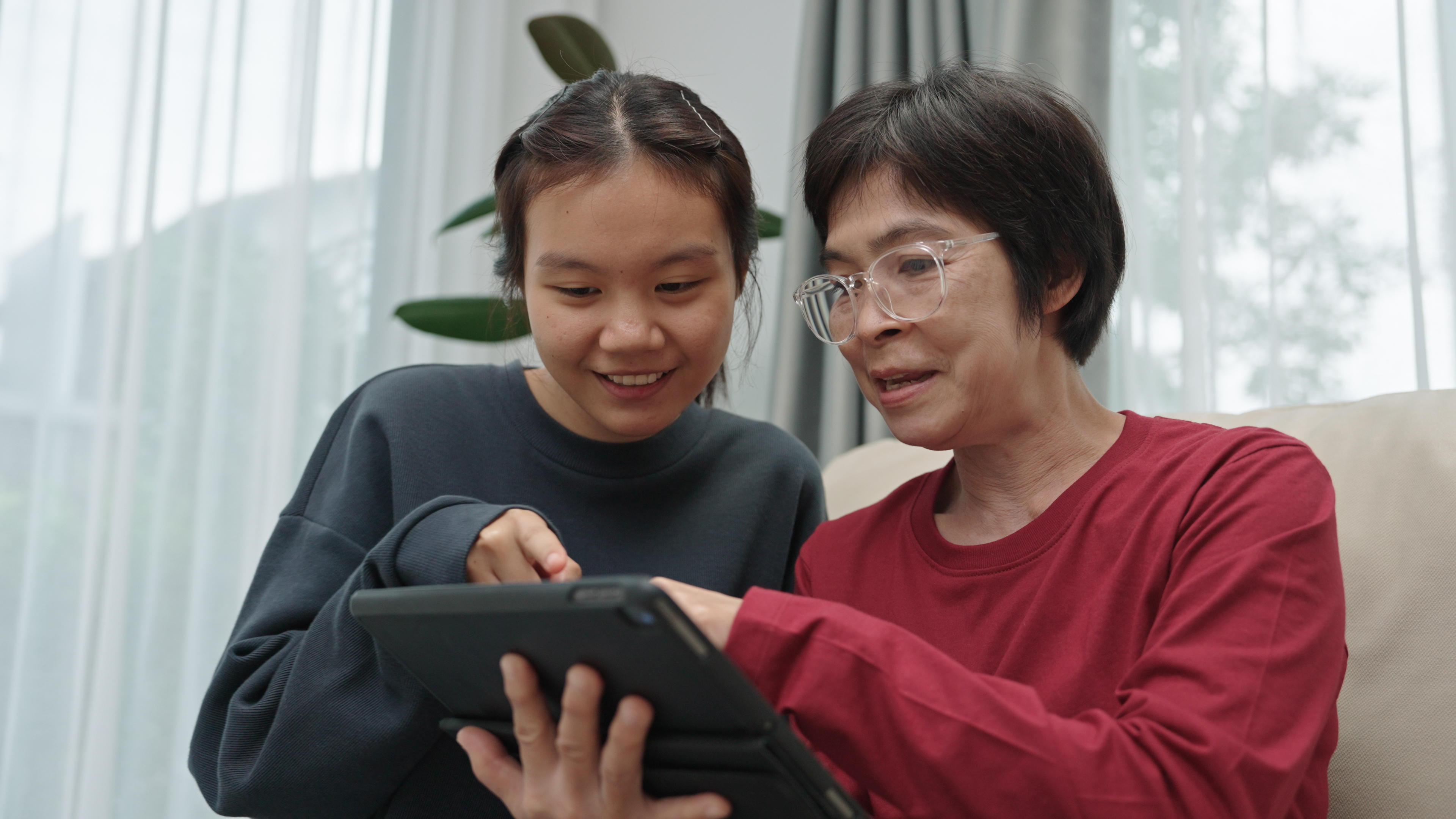 Young girl works with grandma on tablet