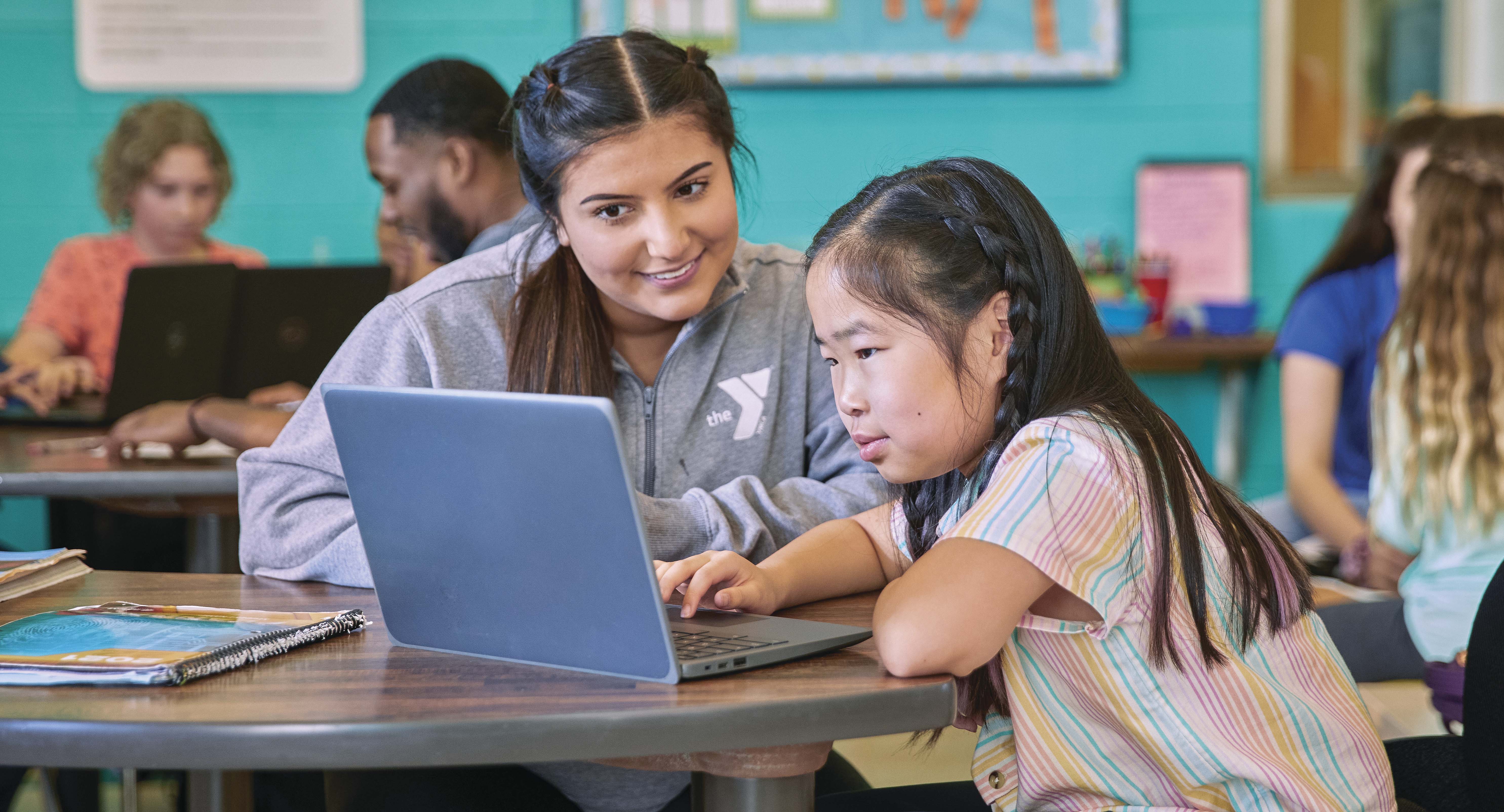 YMCA staff helping girl on computer